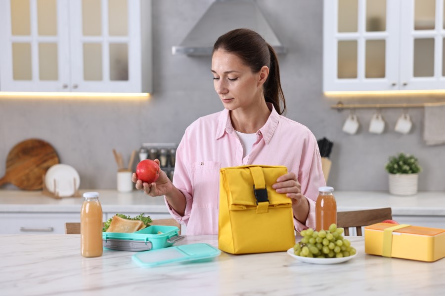 Woman at a kitchen counter prepping her lunch with healthy foods 