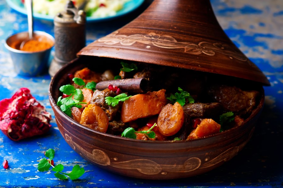 lamb butternut squash and apricots in a tagine on a blue tablecloth