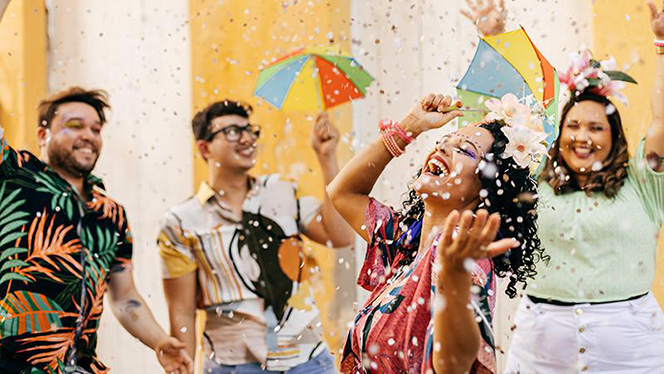 A diverse group of young adults celebrates outdoors.  Confetti is falling on them.