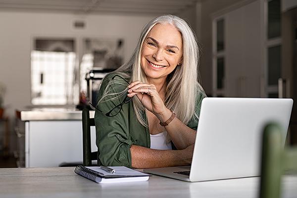 A woman looks up from her laptop while she explores options for Medicare open enrollment.