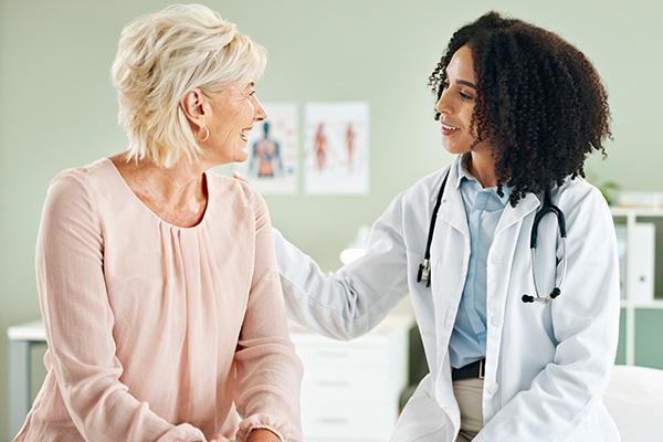 A patient and doctor are having a conversation while the doctor touches the patient's shoulder, highlighting a warm welcome for patients.