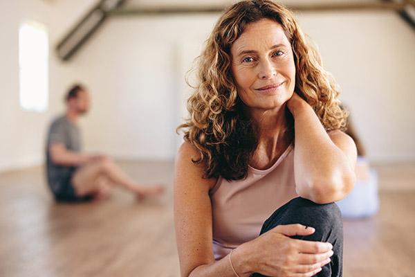 A woman with curly hair sits in a yoga studio, embodying tranquility and the importance of lifestyle changes and strategies to lower your risk of breast cancer.