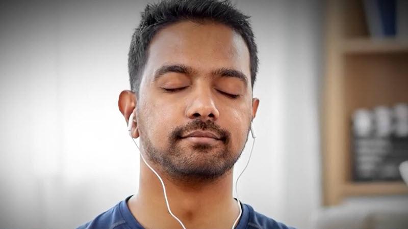 A man, practicing mindfulness, listens to a meditation on his earbuds