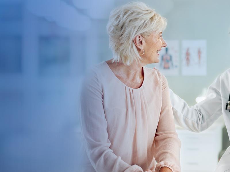 A patient and doctor are having a conversation while the doctor touches the patient's shoulder, highlighting a warm welcome for patients.