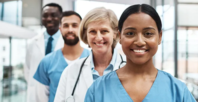 Diverse group of four medical professionals in scrubs lines up diagonally