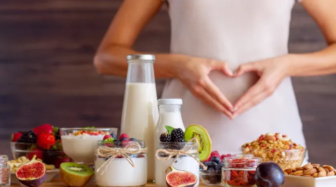 Woman with dysbiosis in front of table of food making a heart with her hands