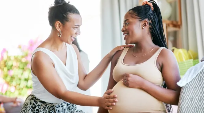 Doula with hand on smiling pregnant woman's tummy