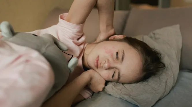 young girl with measles lying in a bed with eyes closed