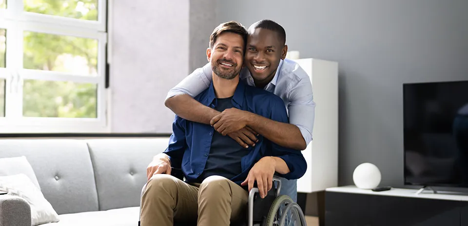 Photo of man in a wheelchair with a man hugging him