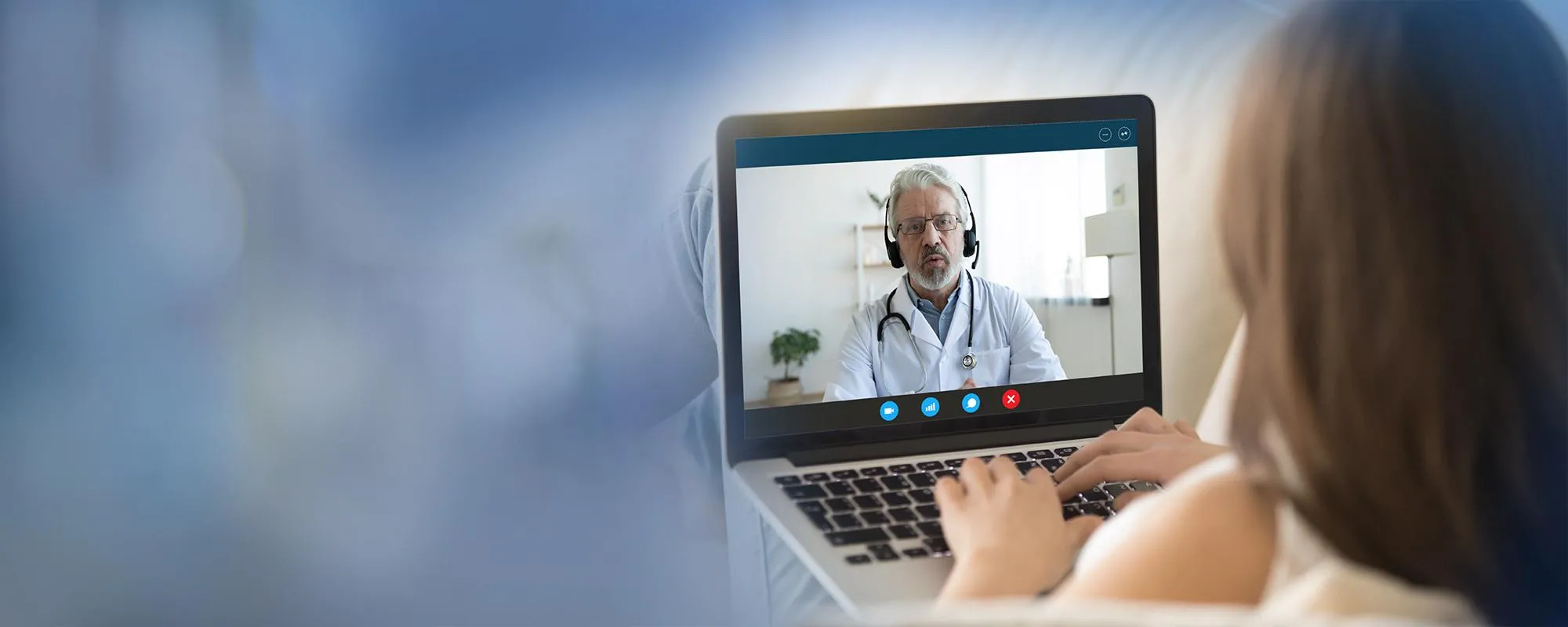 A person is looking at a doctor on a laptop screen during a telehealth appointment.