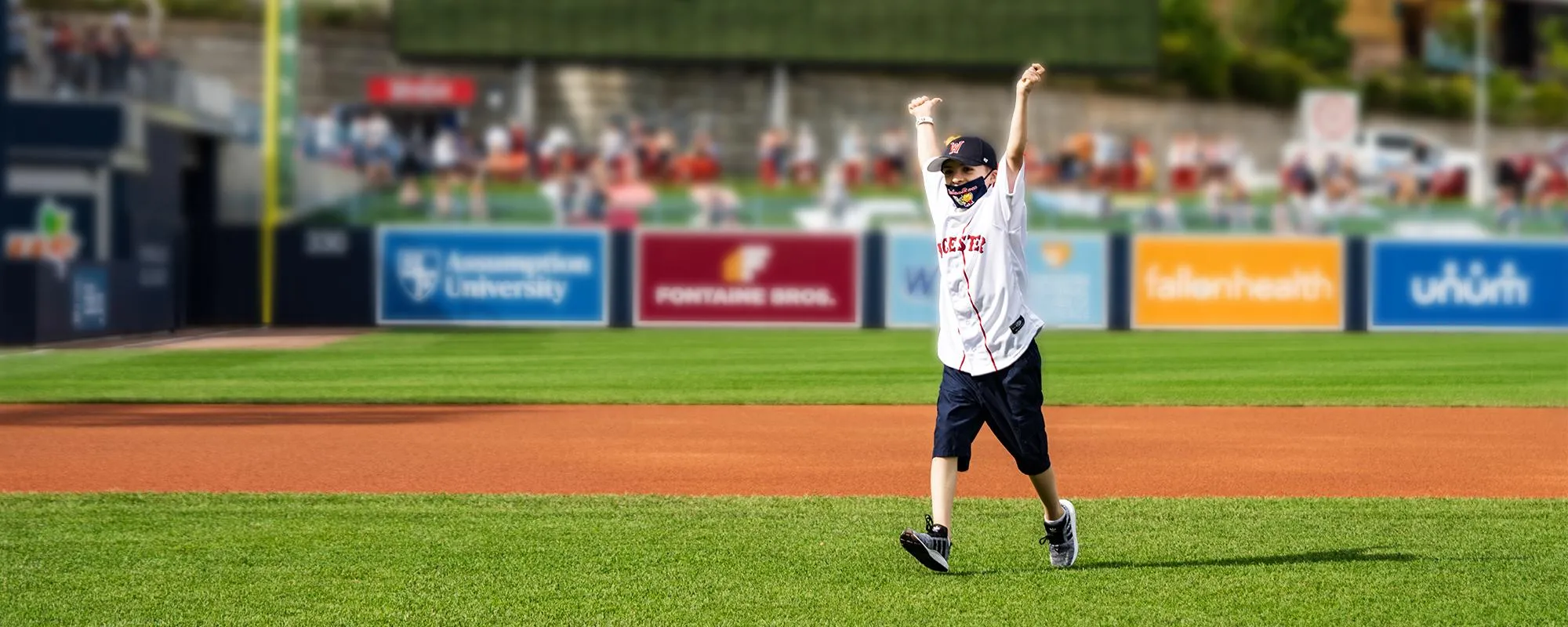 A young boy is running on the field of Polar Park during a Woosox game.