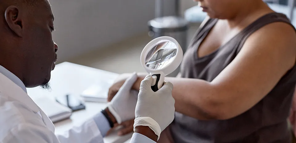 Image of physician examining the skin of a patient