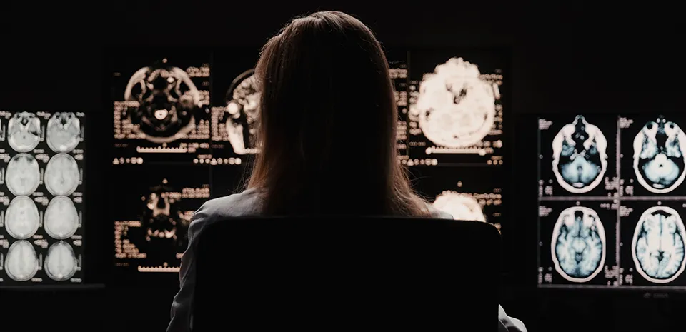 A dark silhouette of a woman is shown reviewing body scan films.