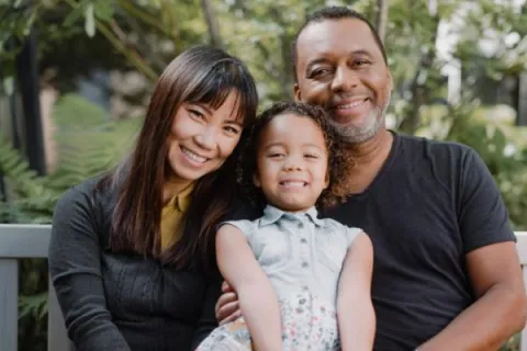 A cheerful family seated on a bench, sharing smiles and laughter in a serene outdoor environment.