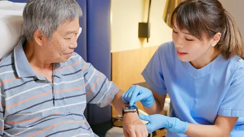 A nurse gently checks the pulse of an elderly man, ensuring his health and well-being during a routine examination.