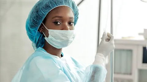 A nurse is shown in full protective wear.