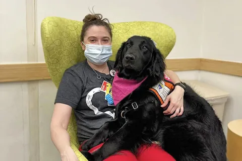 A patient sits with Valentina, our pet therapy dog, during a birthday party.