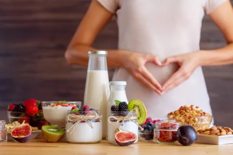 Woman with dysbiosis in front of table of food making a heart with her hands