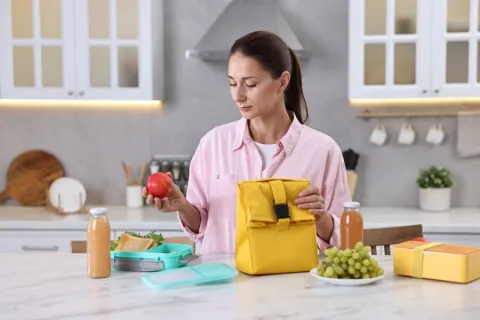 Woman at a kitchen counter prepping her balanced lunch with healthy foods 