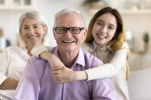 Grandfather with afib being hugged by granddaughter while grandma watches