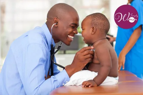 A smiling doctor uses a stethoscope to examine a baby
