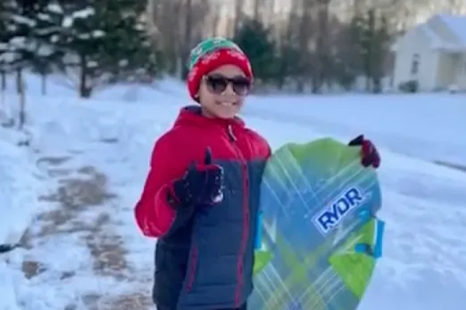 A UMass Memorial Health patient, Chittesh, is giving a thumbs up while holding a snow sled.