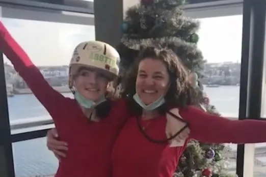 McKenna and another women wear red shirts and celebrate recover in front of a Christmas tree.