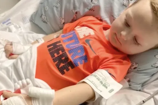 A young boy named Will is resting in a hospital bed at UMass Memorial Health with an IV in his arm.