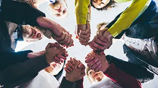 The view from the ground, looking up, to see the six people in a circle holding hands.