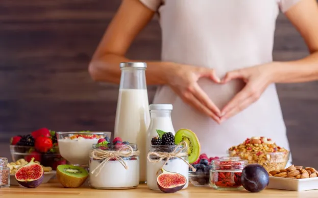 Woman with dysbiosis in front of table of food making a heart with her hands